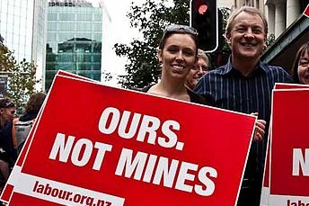 Prime Minister Arden holding ours not mines sign during 2010 march up queen street against mining conservation land